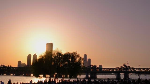 Sunset over the Riverside City with Silhouette of Crowd