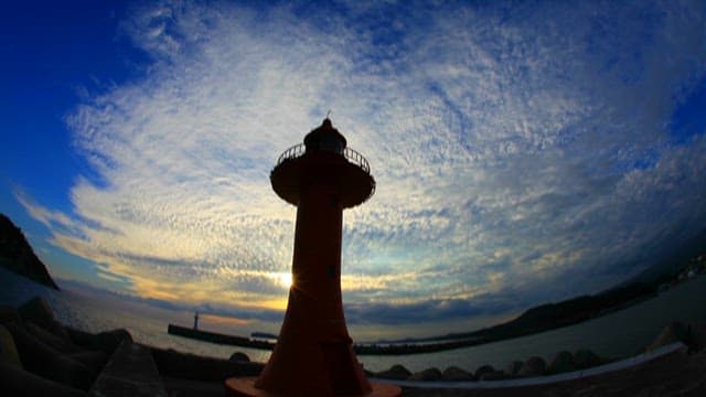 Lighthouse at Sunset with Scattered Clouds