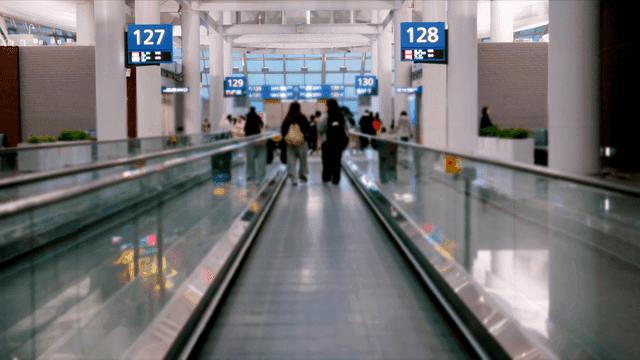 공항 터미널에서 무빙워크를 걷는 사람들