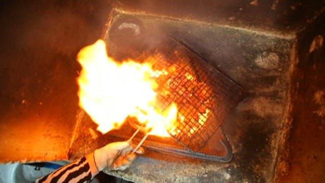 Charcoal-grilling pork belly over open flame