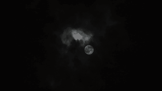 A full moon surrounded by dark clouds