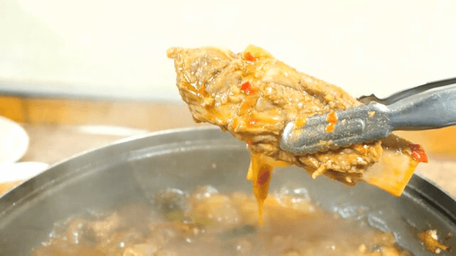 Lifting a piece of meat from the Spicy Braised Pork Galb