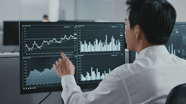 Analysts looking at charts and graphs on monitor