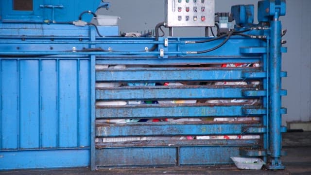 Recycling machine compressing plastic waste in a facility