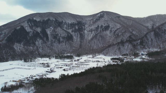 Snow-Covered Village Under Lush Snowy Mountains