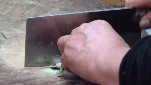 Chinese knife slicing cucumber on wooden cutting board