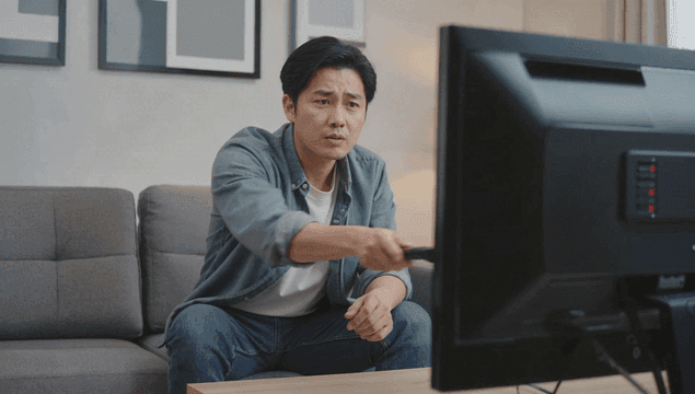 고장난 TV 리모콘을 사용하는 남자