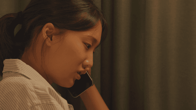 커튼 옆에서 전화 통화 중인 여성