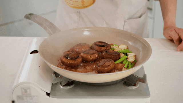 Soy sauce poured over mushrooms and vegetables in pan