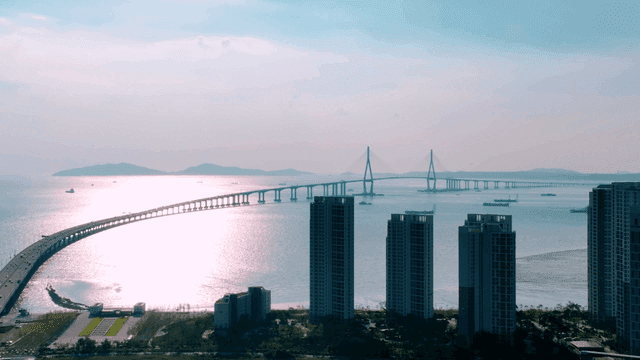 Bridge and high-rise buildings next to sunlit sea