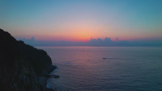 Sunset over a calm ocean with distant boats