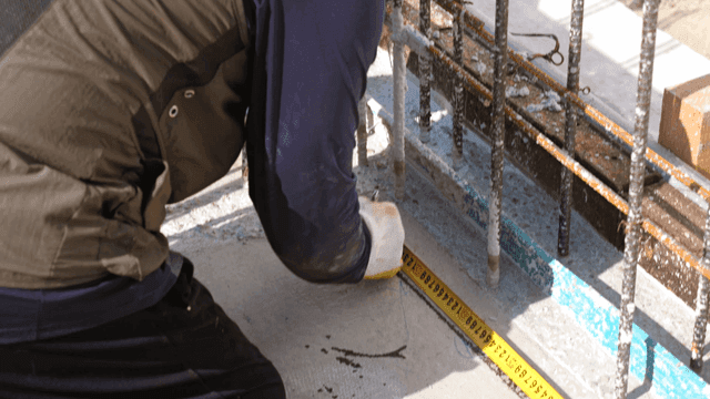 줄자로 콘크리트를 측정하는 작업자