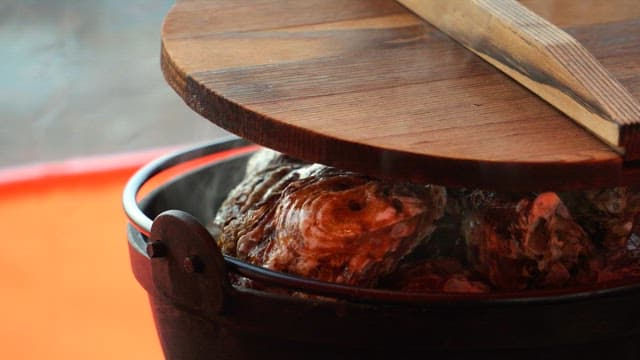 Steaming oysters in a pot with a wooden lid