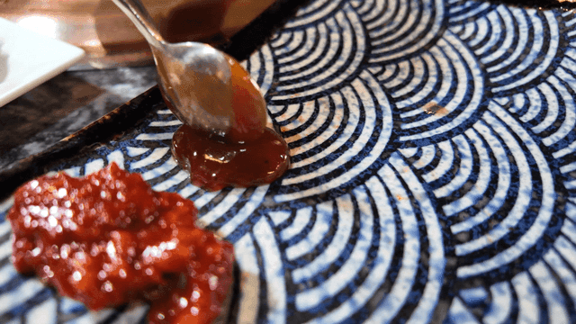 Scene of placing sauce on patterned plate in front of grill