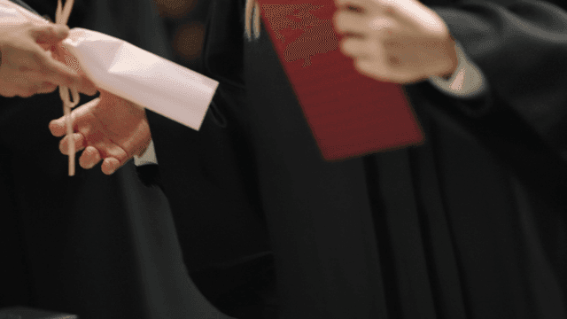 Graduates wearing graduation gowns and holding diplomas