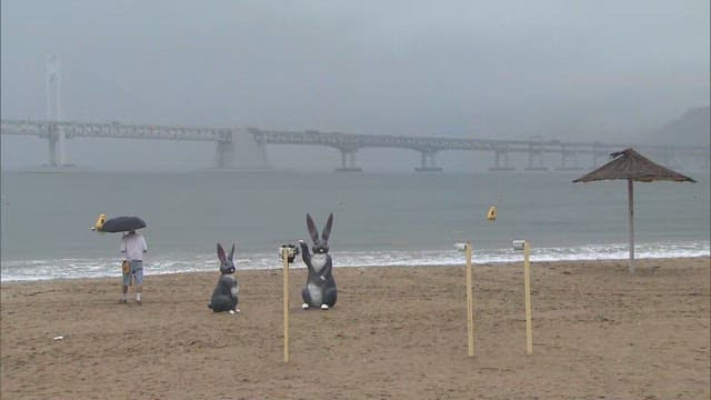 Foggy day at a beach with sculptures and visitors