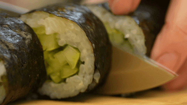 Cucumber gimbap being precisely sliced