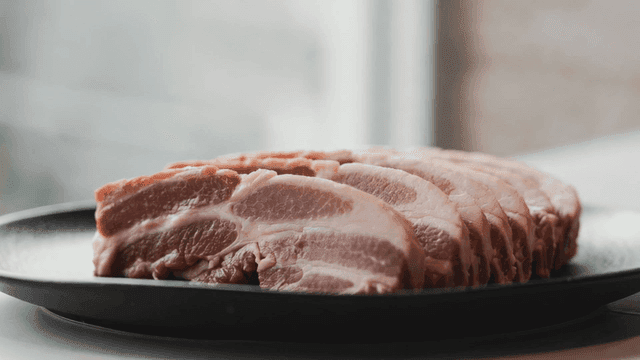 Slices of raw pork on a black plate