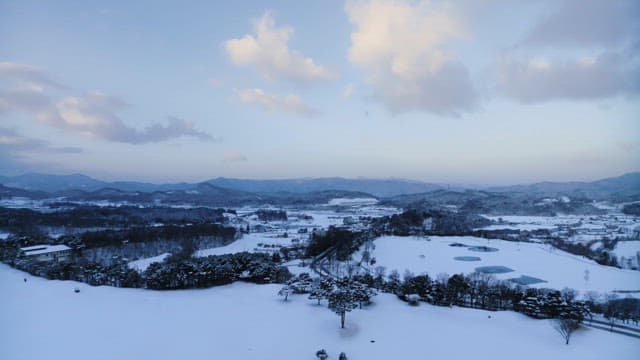 Snow-covered landscape at dusk with hills