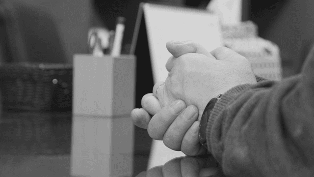 Hands clasped on an office desk
