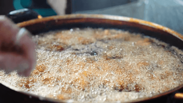 Hands frying chicken in hot oil