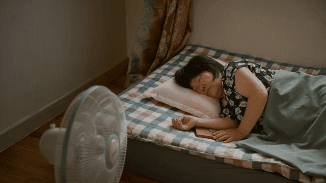 선풍기를 켜고 잠든 노인 여성