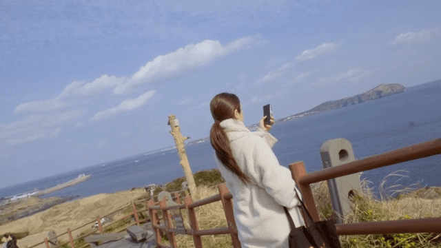 스마트폰으로 바다 경치를 찍는 여성