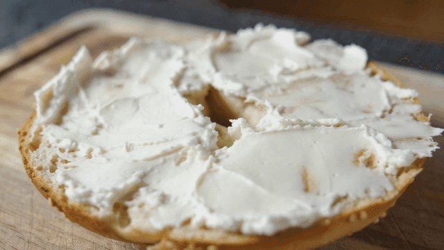 Bagel with cream cheese on a wooden board