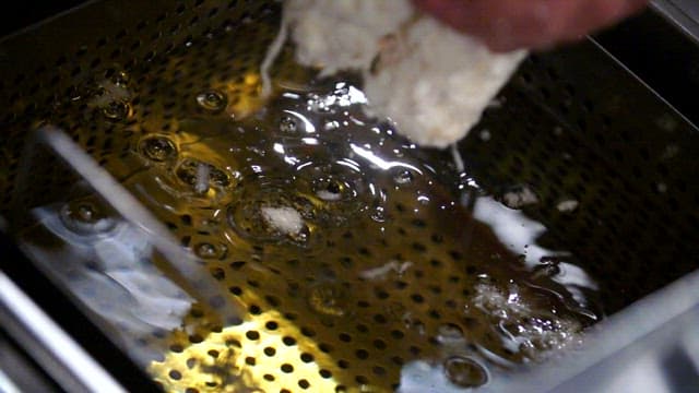 뜨거운 기름에 빵가루를 묻힌 돈가스를 튀기기