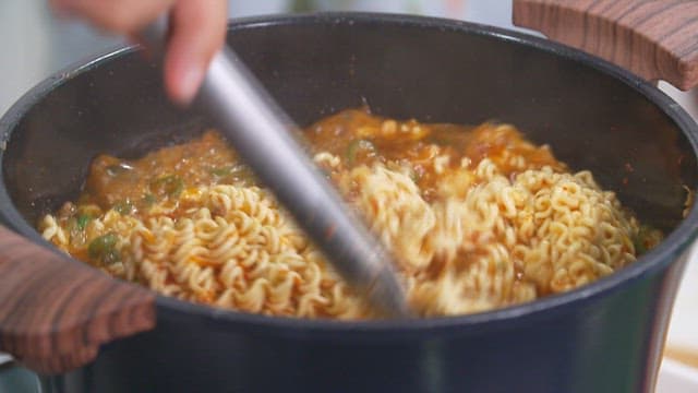 Delicious ramen boiling in a pot with tongs