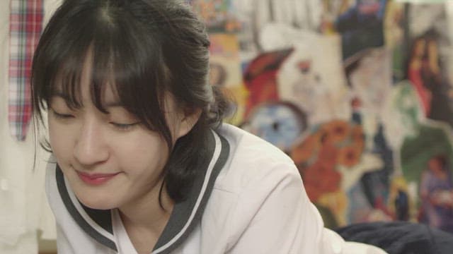 알록달록한 벽지가 있는 방에 엎드려 있는 여학생