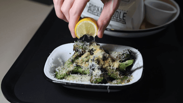 Squeezing lemon over cheese-topped broccoli dish