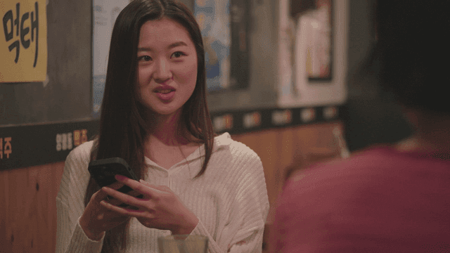 Young woman using a phone while talking at a pub
