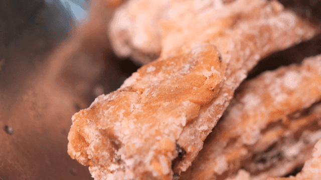 Scraping outer layer of fried ribs with knife in kitchen