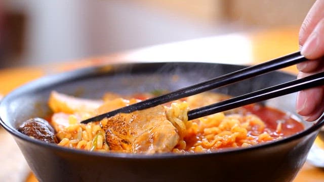 젓가락으로 돼지고기와 라면을 집는 모습