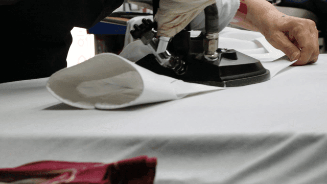 Person ironing white fabric indoors