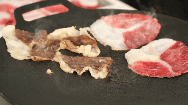 Sliced ​​pork belly sizzling on hot grill