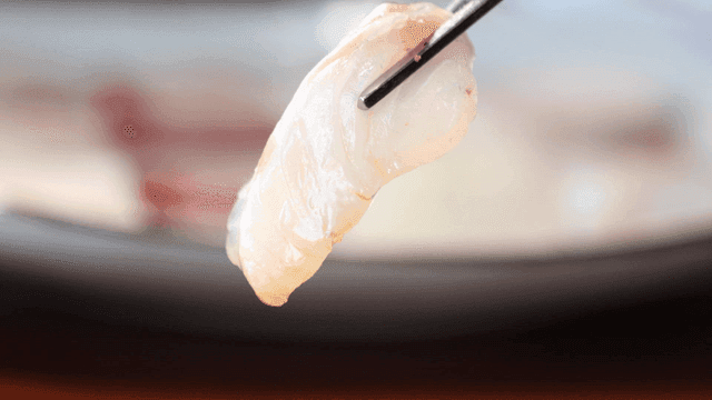 Fresh sea bass sashimi dipped in soy sauce