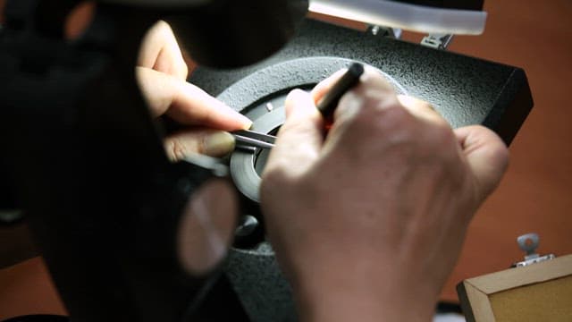 밝은 빛 아래서 빨간 보석을 세공하는 모습