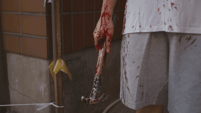 Hand holding a blood-stained hammer and clothes