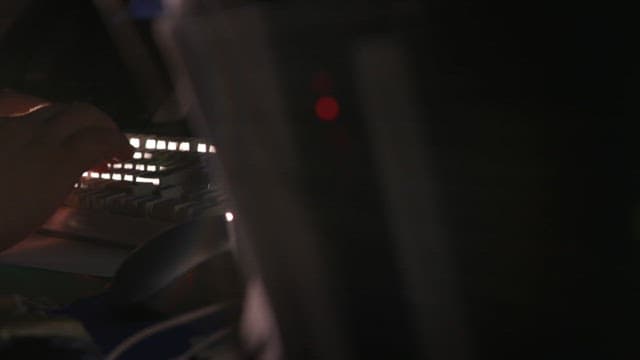 Hands typing on a keyboard in a dark room