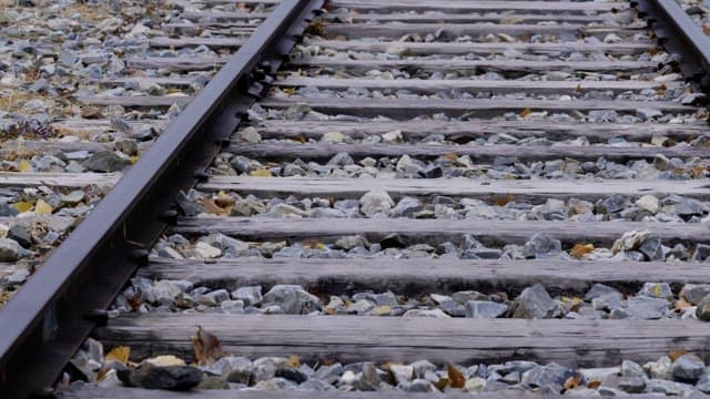 Long track of gravel and metal rails on a foggy morning