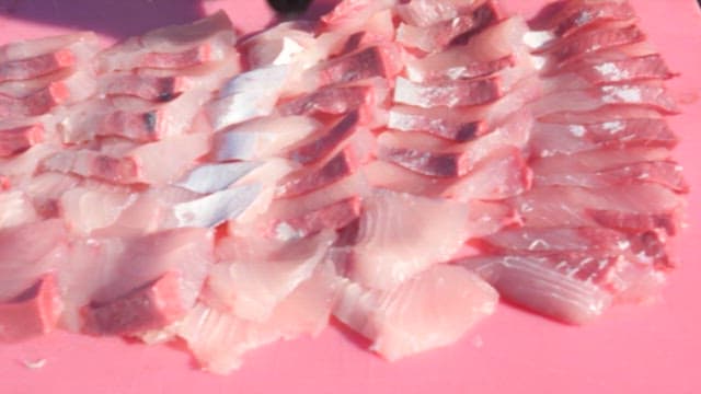 Freshly sliced yellow tail on a pink cutting board