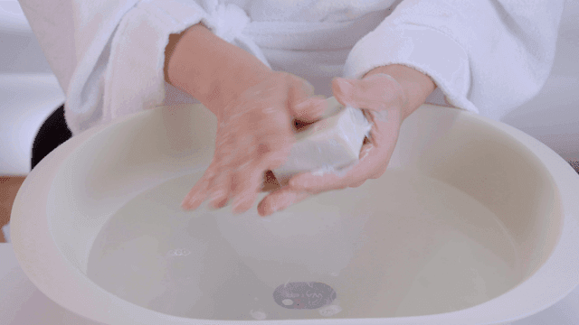 Person washing his hands with soap in basin