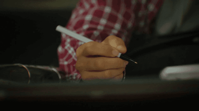 A person writing with a pen indoors