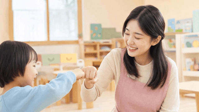 Teacher and child exchanging fist bumps at kindergarten