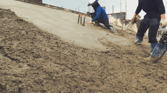 Workers smoothing wet concrete on a slope
