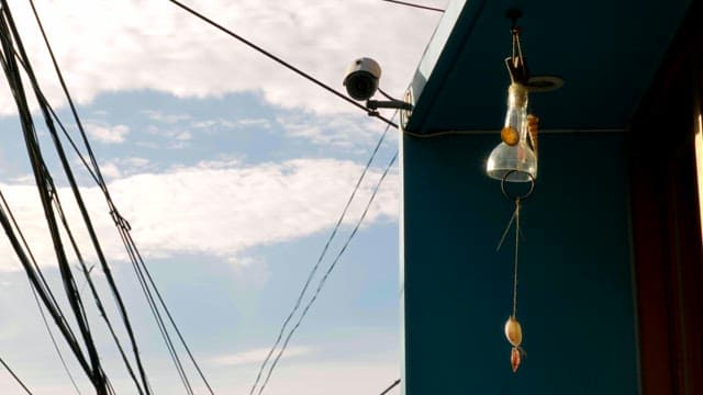 Security camera and wind chime on a building