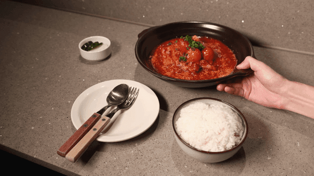 Table set with rice and kimchi stew topped with cherry tomatoes