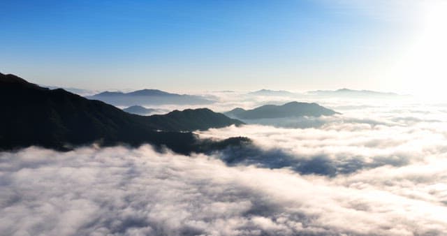 Mountains covered in clouds under a clear sky